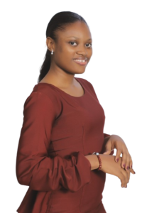 Image of Jane Oluwadare. in a wine dress. She is turned sideways, with her hands crossed softly in front of her at the waist level. Her hair is slicked back in a low ponytail